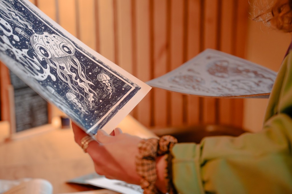 Photographie d'une artiste bretonne en train de tenir deux œuvres, par Charles Menguy