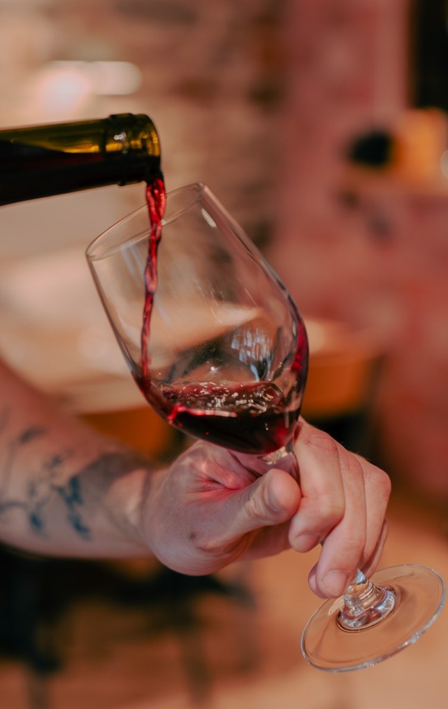 Photographie lifestyle d'un verre dans lequel du vin est versé, par Charles Menguy