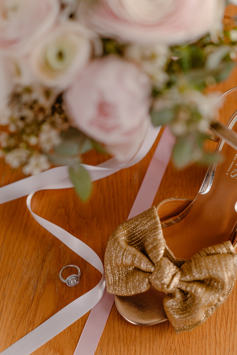 Photographie de détails de mariage, dont le bouquet, une chaussure de la mariée et l'alliance