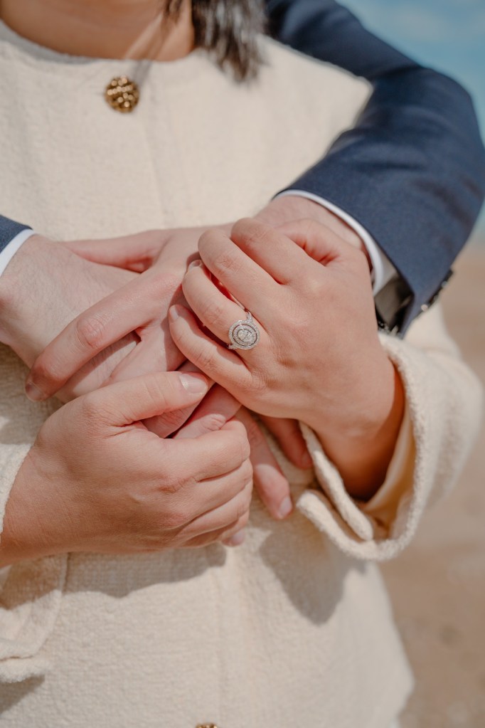 Photographie lifestyle d'un couple de jeunes mariés qui s'enlacent. On voit la bague de fiançaille