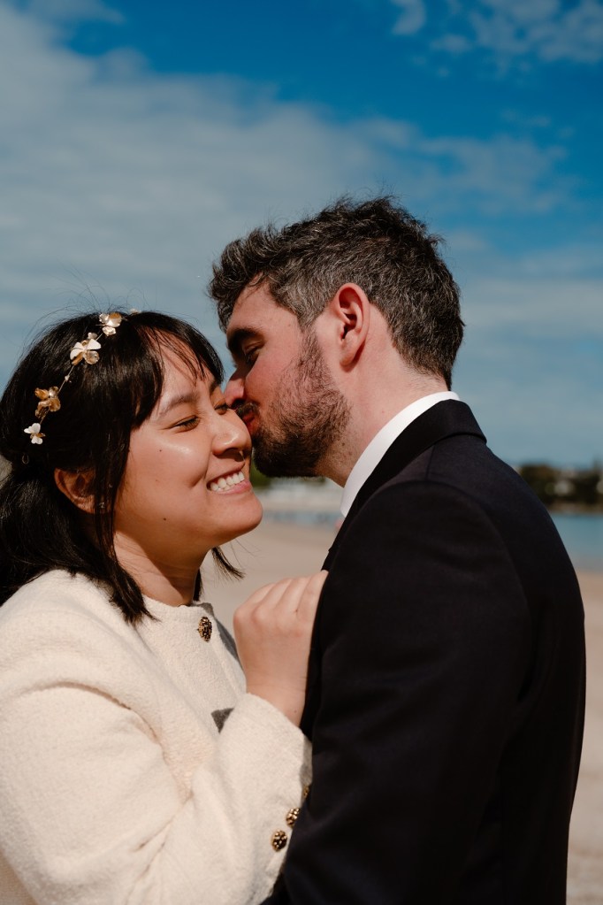 Le marié embrasse la mariée sur une plage en Bretagne
